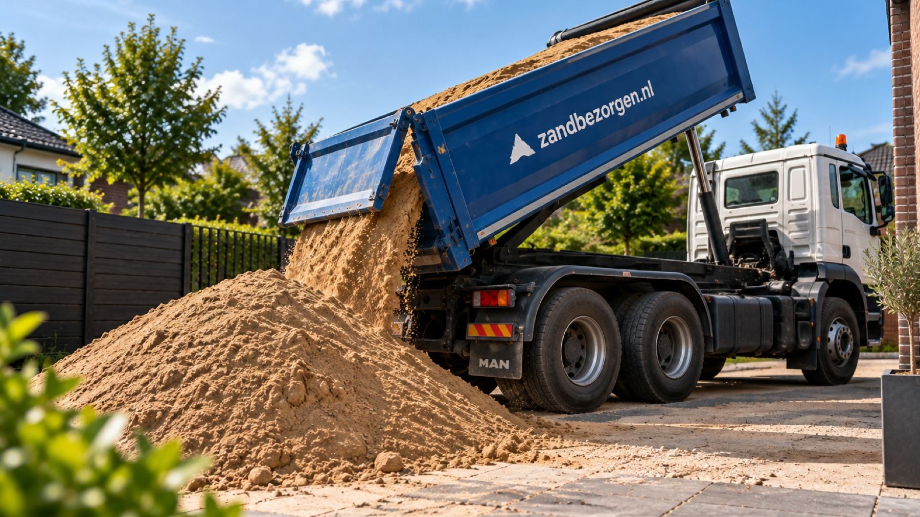 Kiepwagen van Zandbezorgen lost zand op een oprit